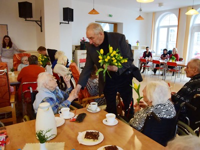 Zástupci města Jablonec přichází za ženami s květinou