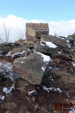 Zničený kamenný pomník ve tvaru kříže u rozhledny Štěpánka